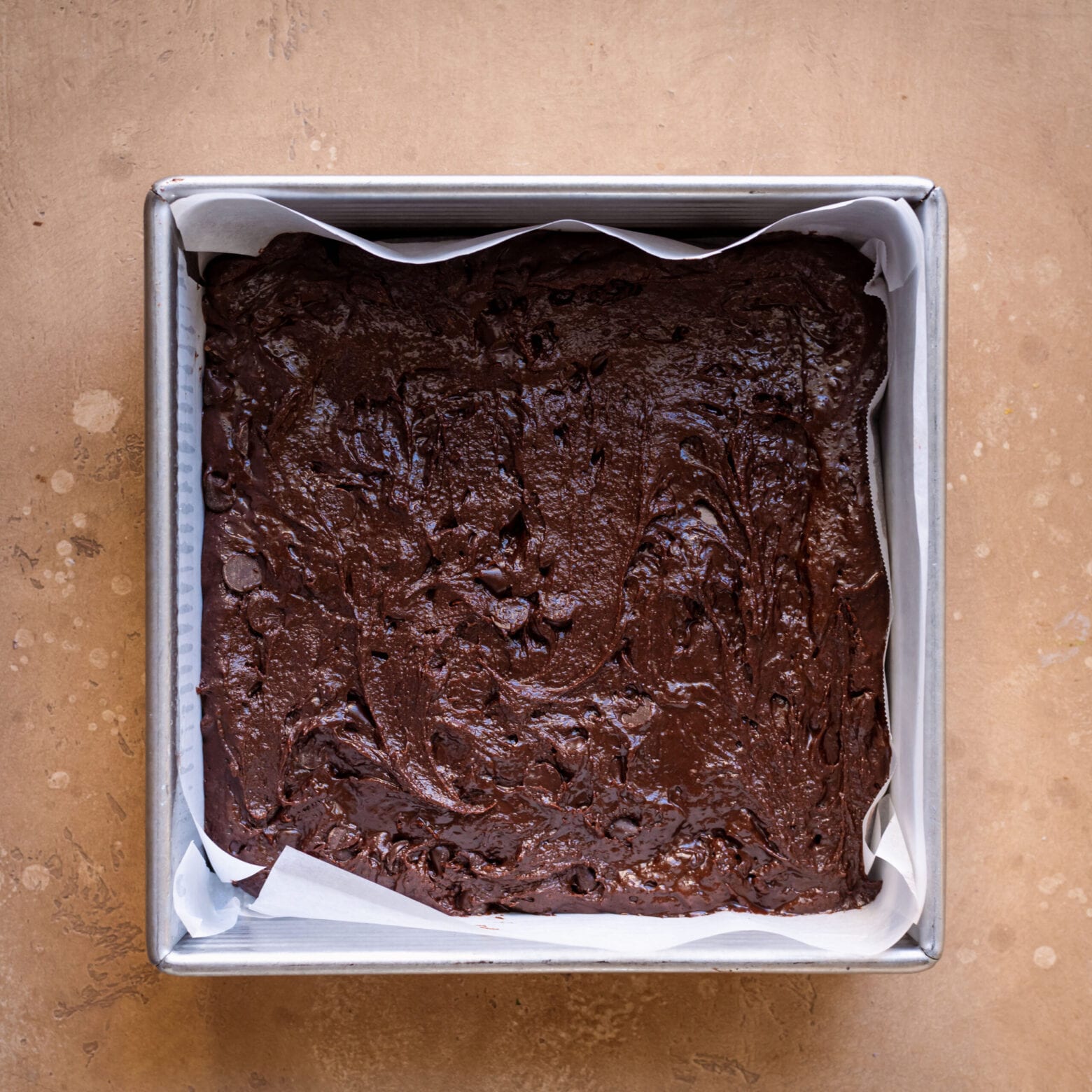 brownie batter in 8x8 baking pan lined with parchment paper