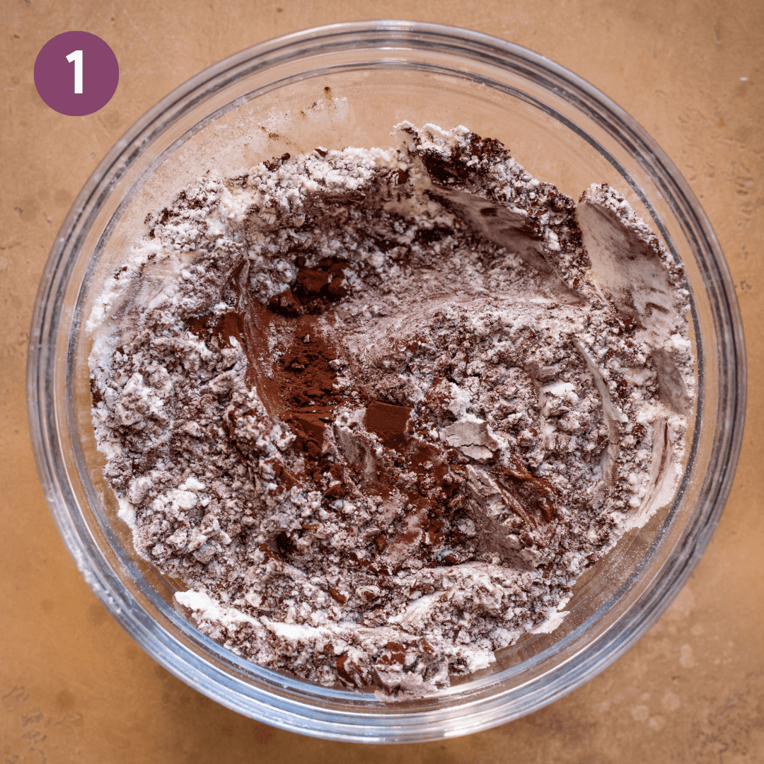 dutch cocoa process powder mixed with flour in a glass bowl on brown table.