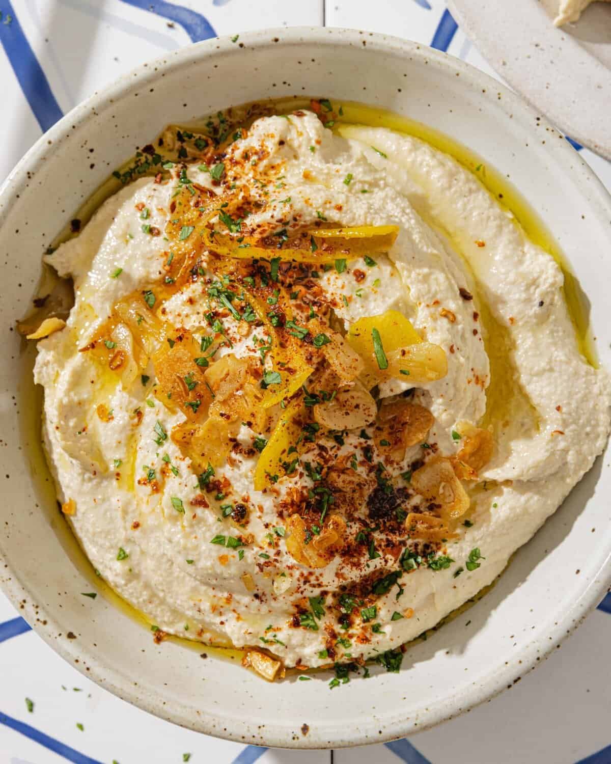 overhead view of homemade hummus with lemon garlic topping in a bowl.