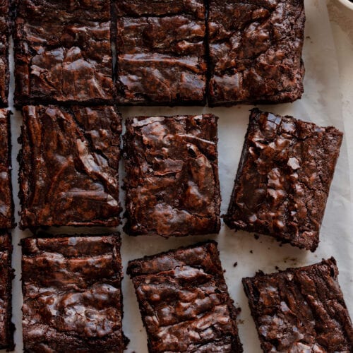 the best vegan brownies with a shiny top sitting on parchment paper