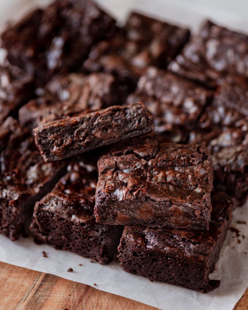 a stack of the best fudgy vegan brownies sitting on parchment paper