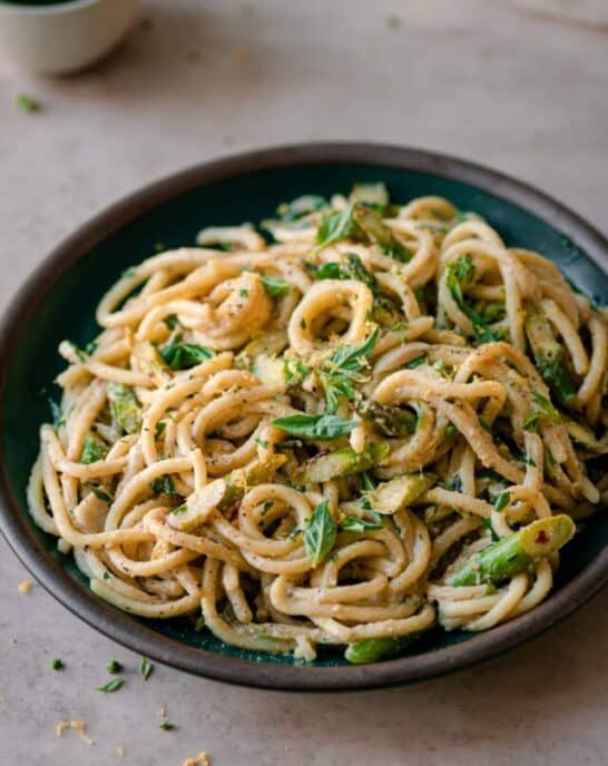 shallow bowl of creamy lemon asparagus pasta on neutral backdrop.