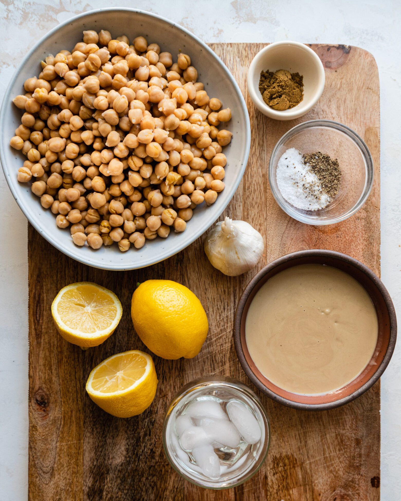 chickpeas, tahini, lemons, garlic on cutting board - ingredients for hummus