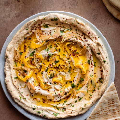 Plate of creamy hummus with olive oil and herbs with pita bread