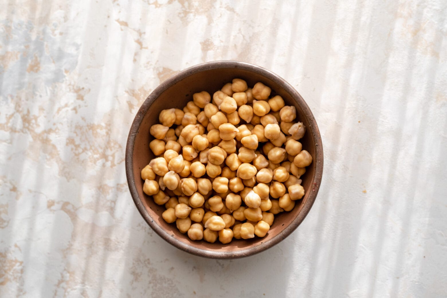 bowl of soaked chickpeas in a bowl on marbled surface