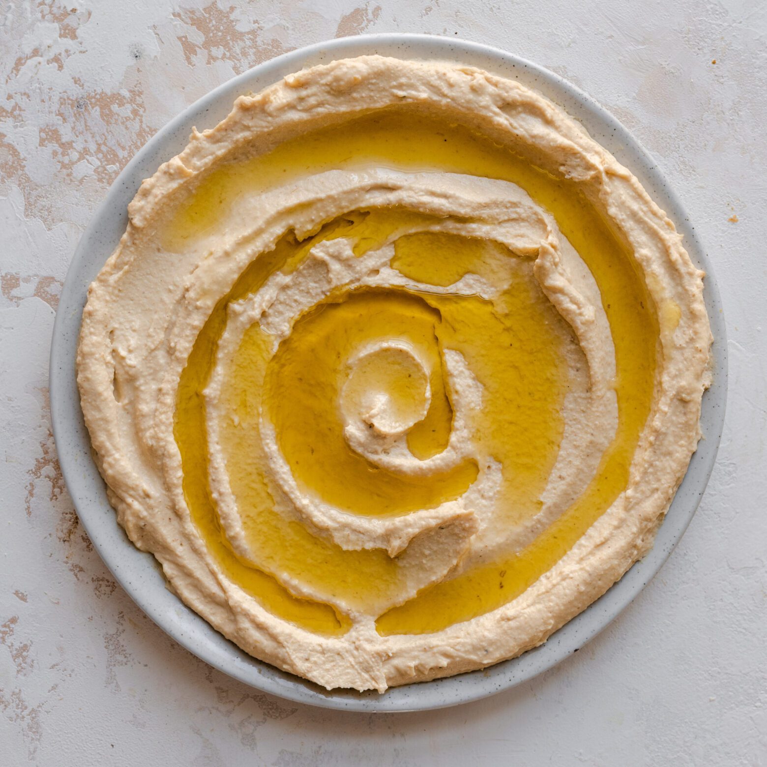 creamy hummus swirled on plate with olive oil on top