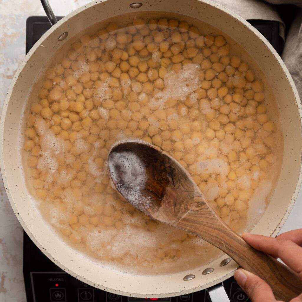 skimming foam off of surface of chickpeas in saucepan