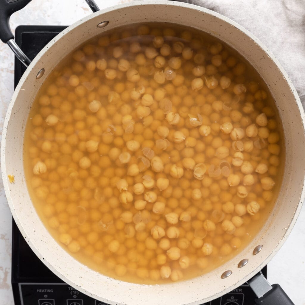 soft cooked chickpeas with loose skins in saucepan