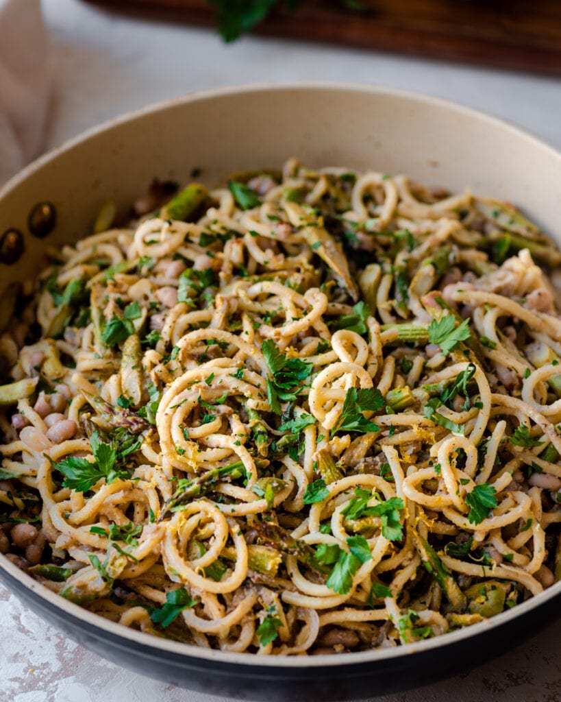 pan full of spaghetti with fresh herbs and lemon zest.