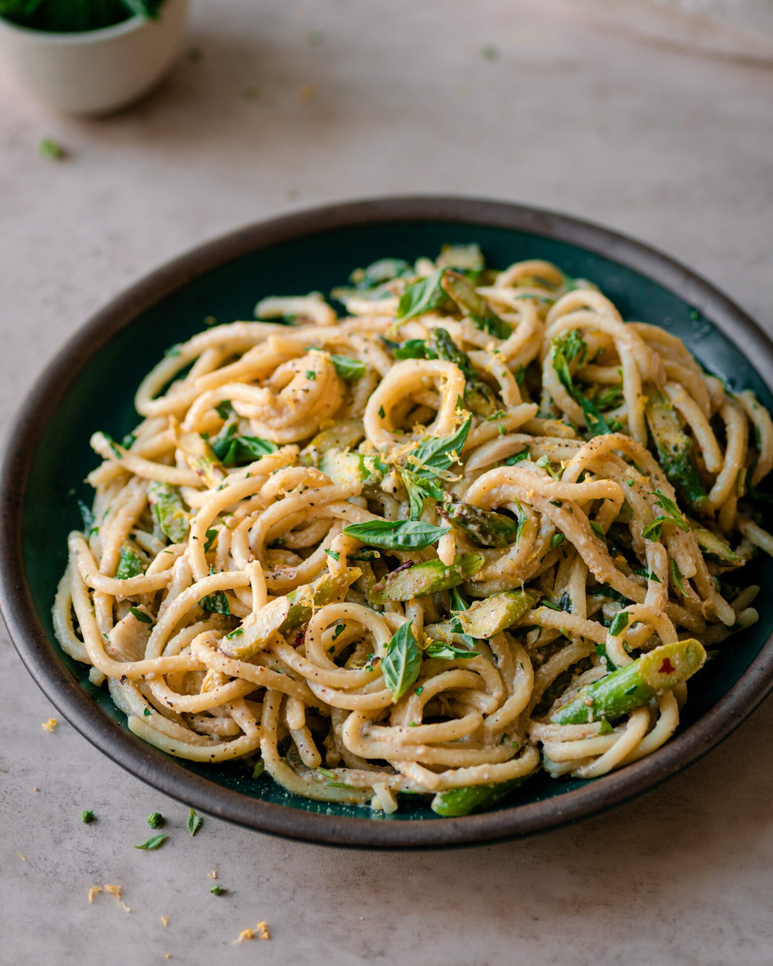 Shallow bowl of creamy lemon asparagus pasta on neutral background