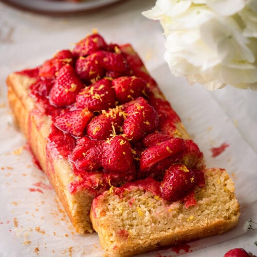 lemon olive oil cake on parchment paper with strawberry sauce on top