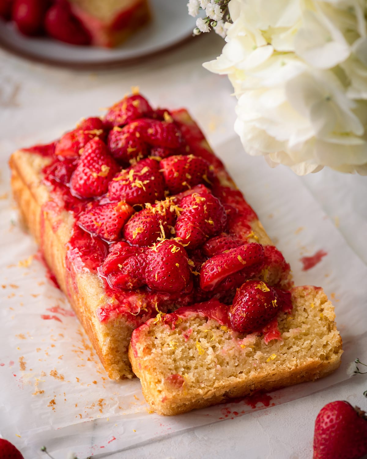 lemon olive oil cake on parchment paper with strawberry sauce on top