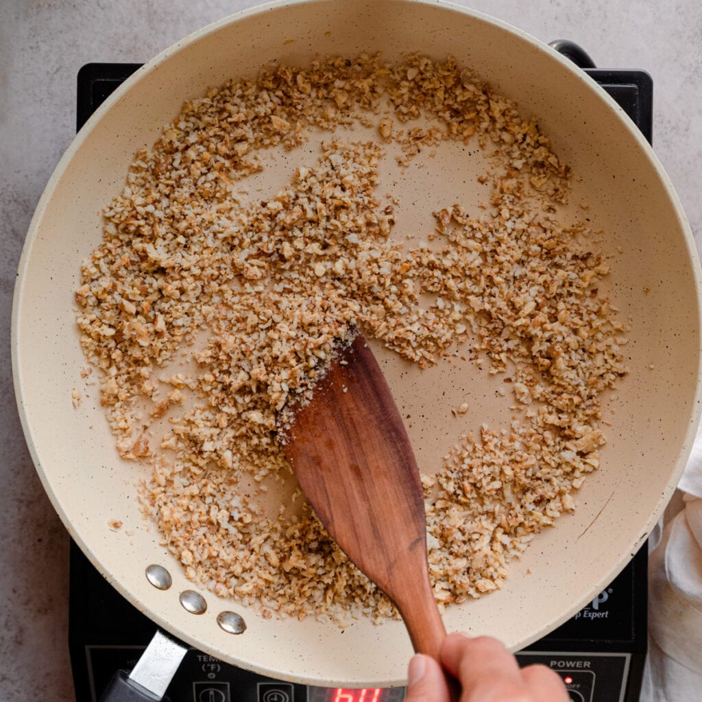 stirring walnuts and bread crumbs in saute pan