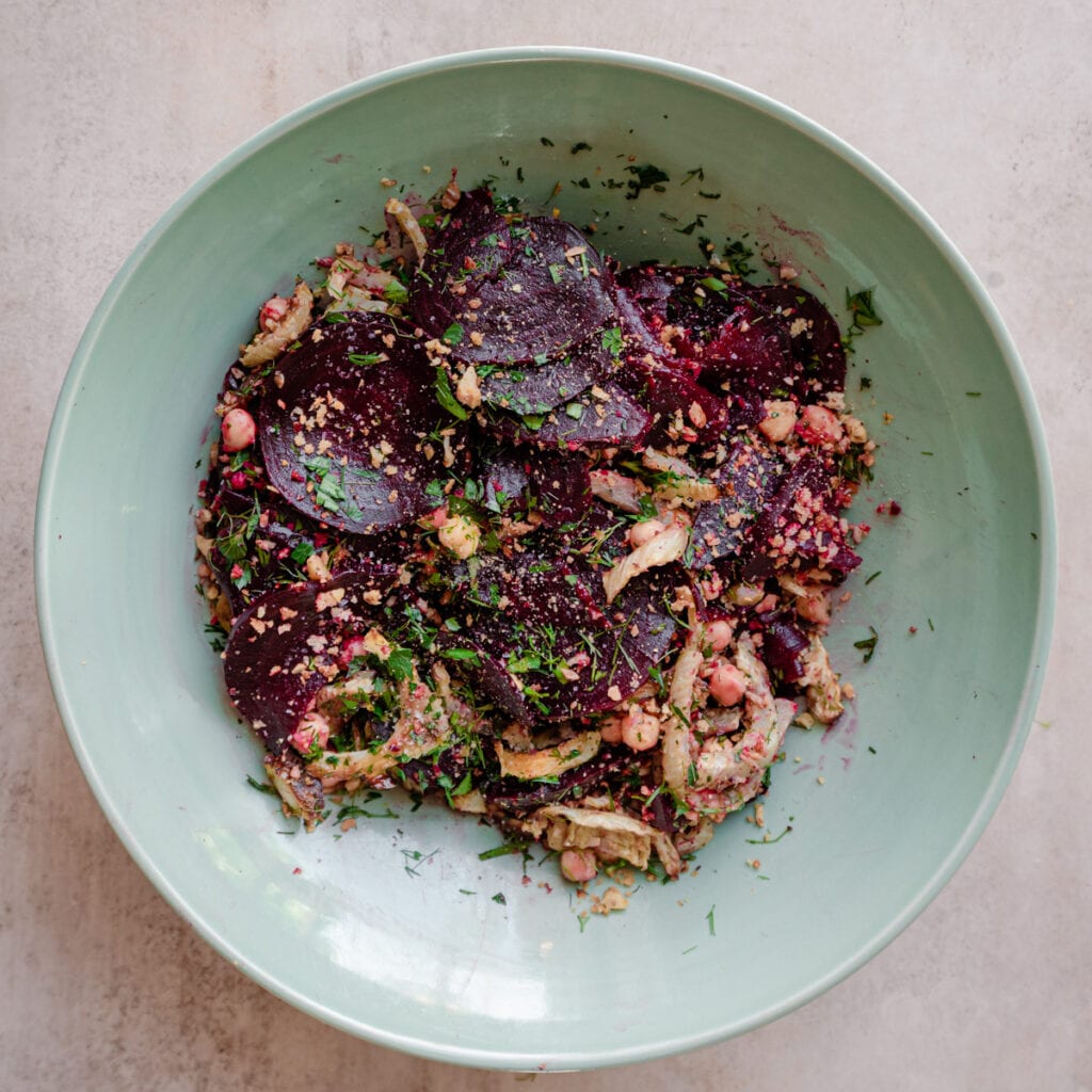 roasted beet salad with herbs and nuts in large bowl 