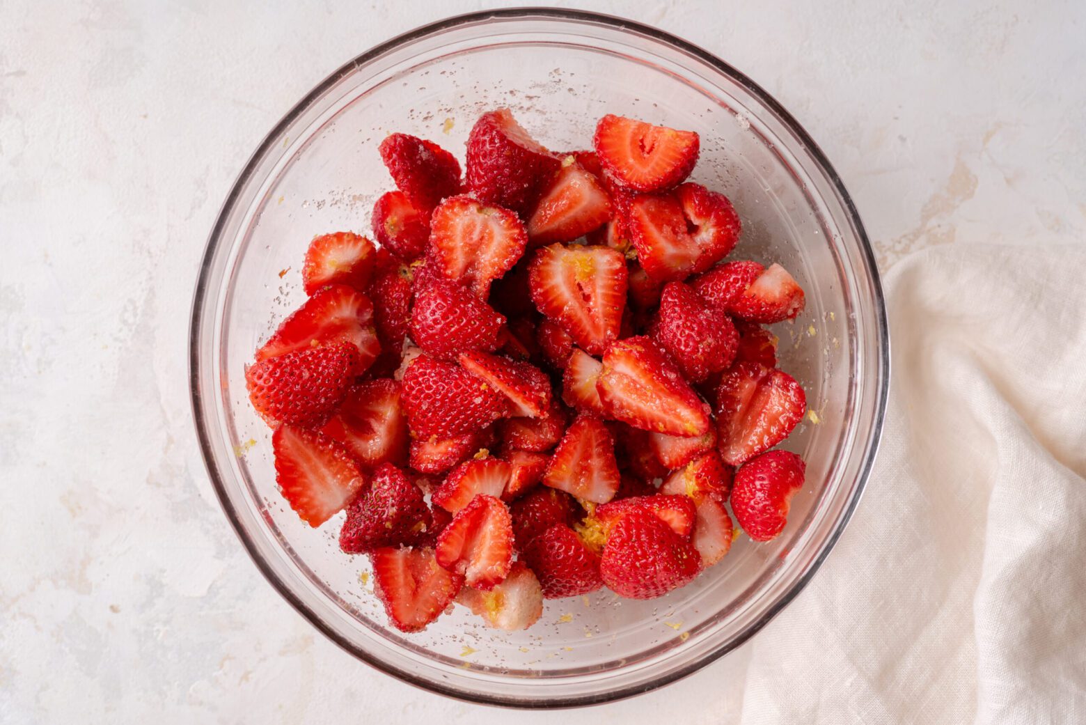 bowl of strawberries macerating with sugar and lemon zest