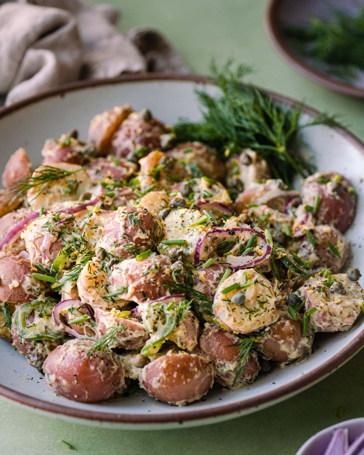 closeup photo of vegan potato salad with dilll in a large white bowl