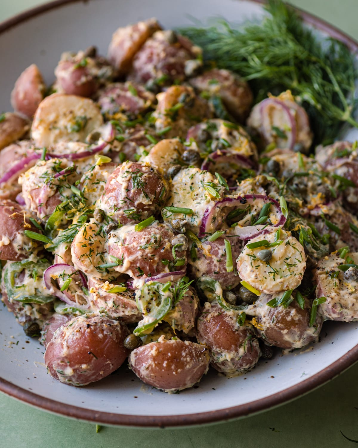 closeup photo of vegan potato salad with dilll on a white platter