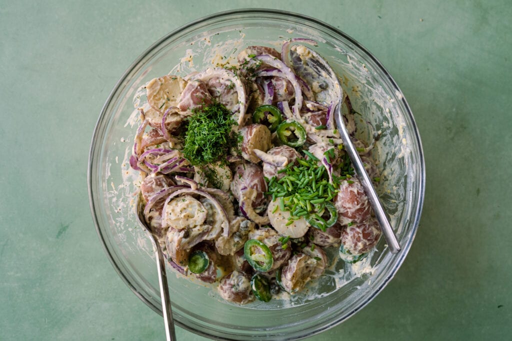 adding chives and dill to vegan potato salad