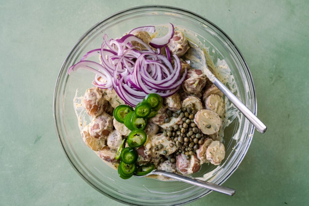 adding onions and capers to potato salad