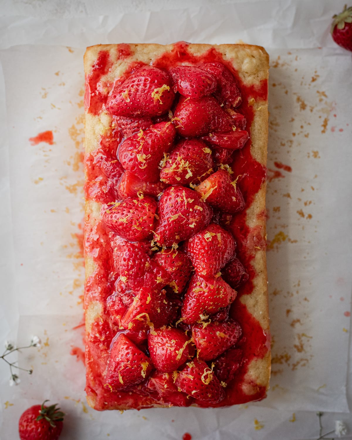 overhead shot of finished lemon olive oil cake with strawberry compote and lemon zest on top