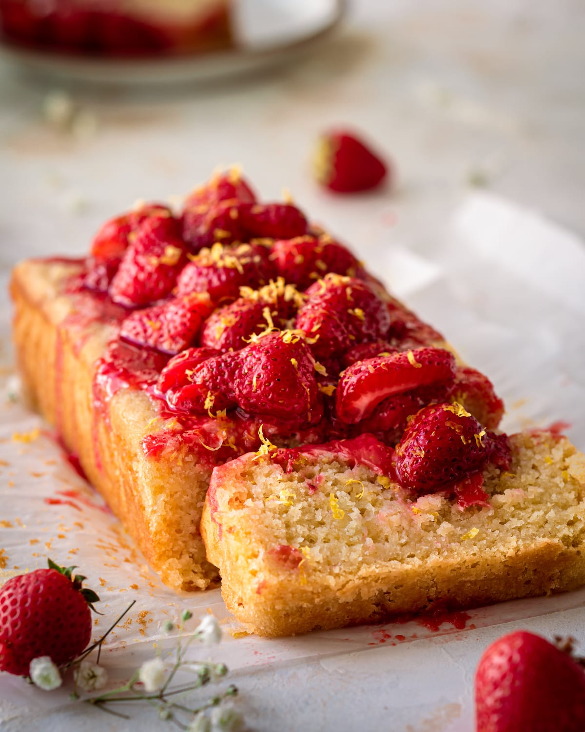 lemon olive oil cake on parchment paper with strawberry sauce on top