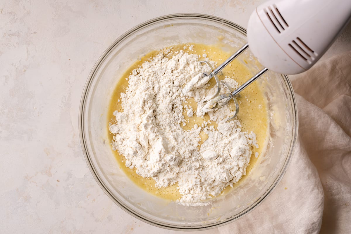 mixing second batch of flour into liquid cake batter with electric mixer