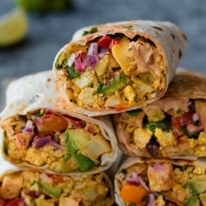 a closeup photo of a stack of vegan breakfast burritos on a blue backdrop