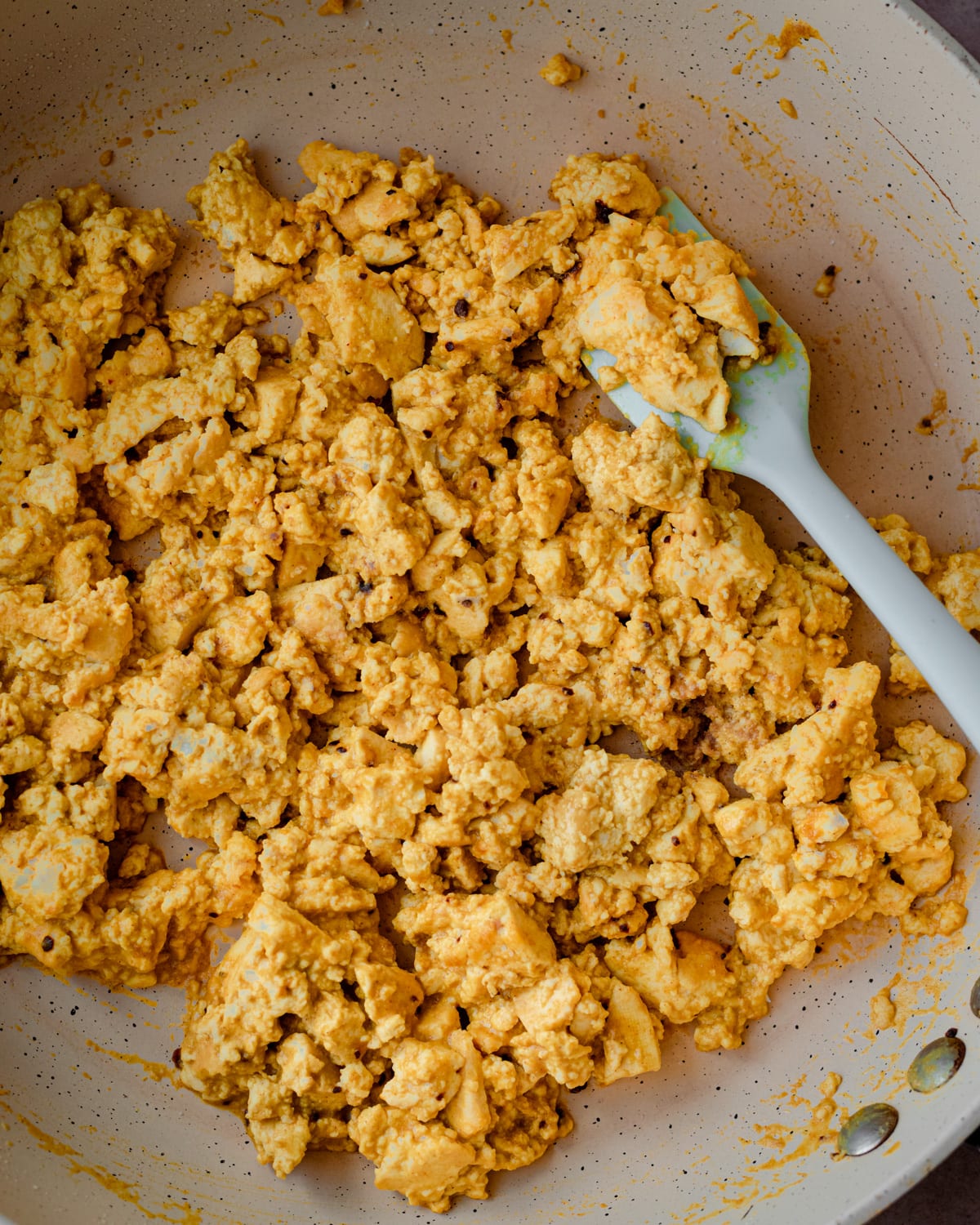 eggy tofu scramble in frying pan with spatula.