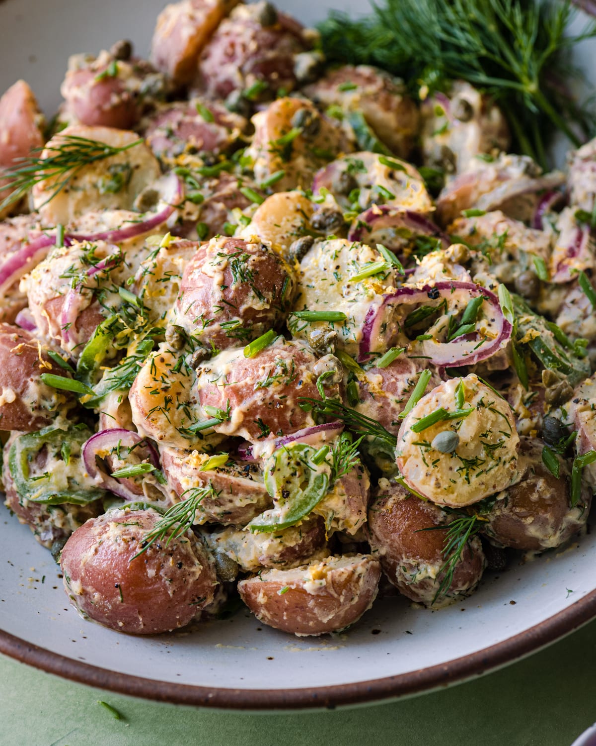 close-up of vegan potato salad with onions and jalapeno peppers visible.