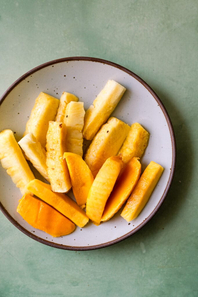 white plate with pineapple spears and mango slices