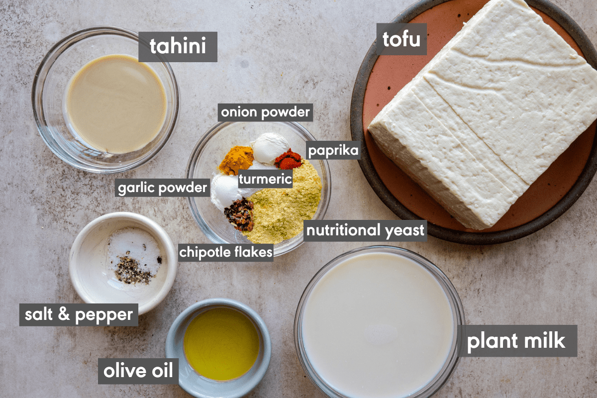 ingredients for tofu scramble on a light pink surface with ingredients labeled.