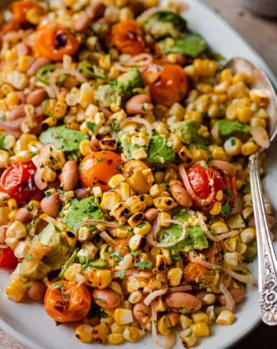 grilled corn salad with cherry tomatoes and avocado on serving platter.