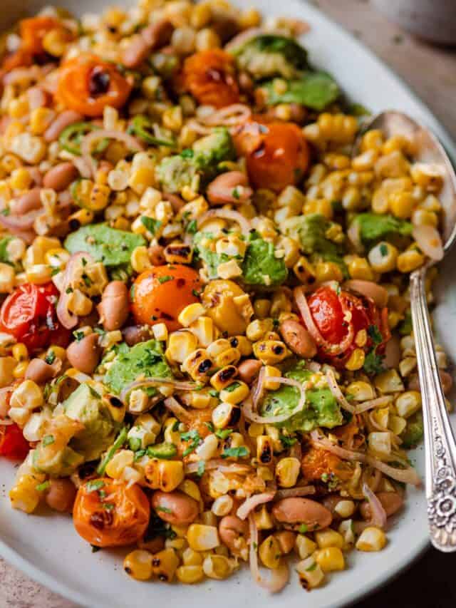 grilled corn salad with cherry tomatoes and avocado on serving platter.