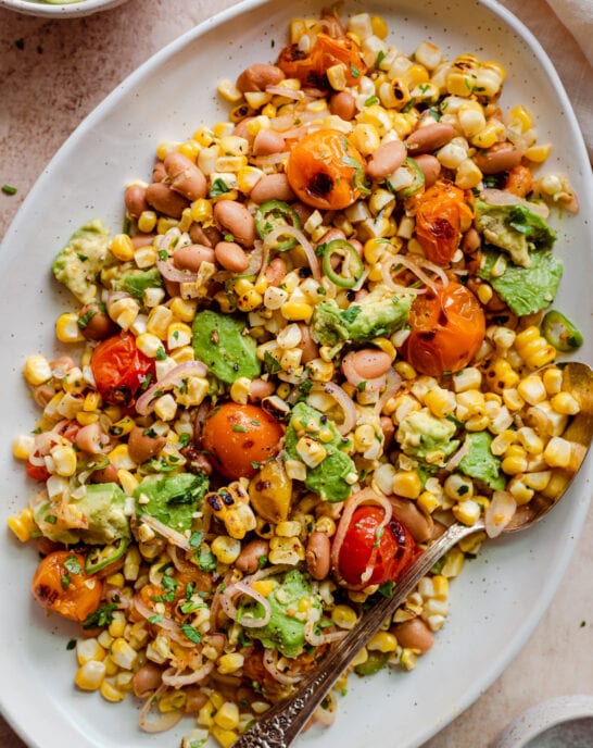 grilled corn salad with cherry tomatoes and avocado on serving platter