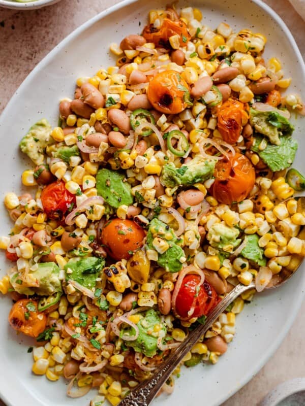 grilled corn salad with cherry tomatoes and avocado on serving platter