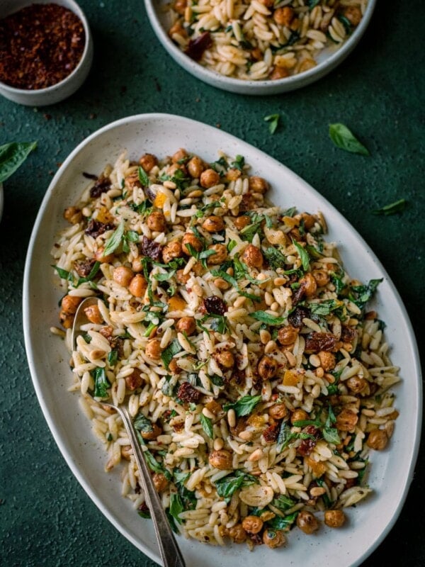 lemon orzo pasta salad on white tray on dark green backdrop