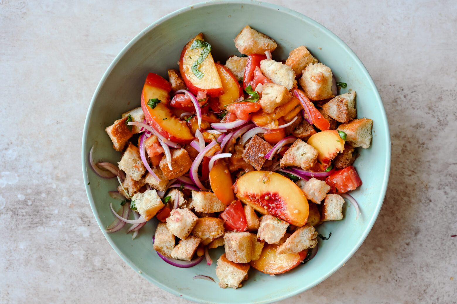 peach panzanella salad ingredients in a serving bowl