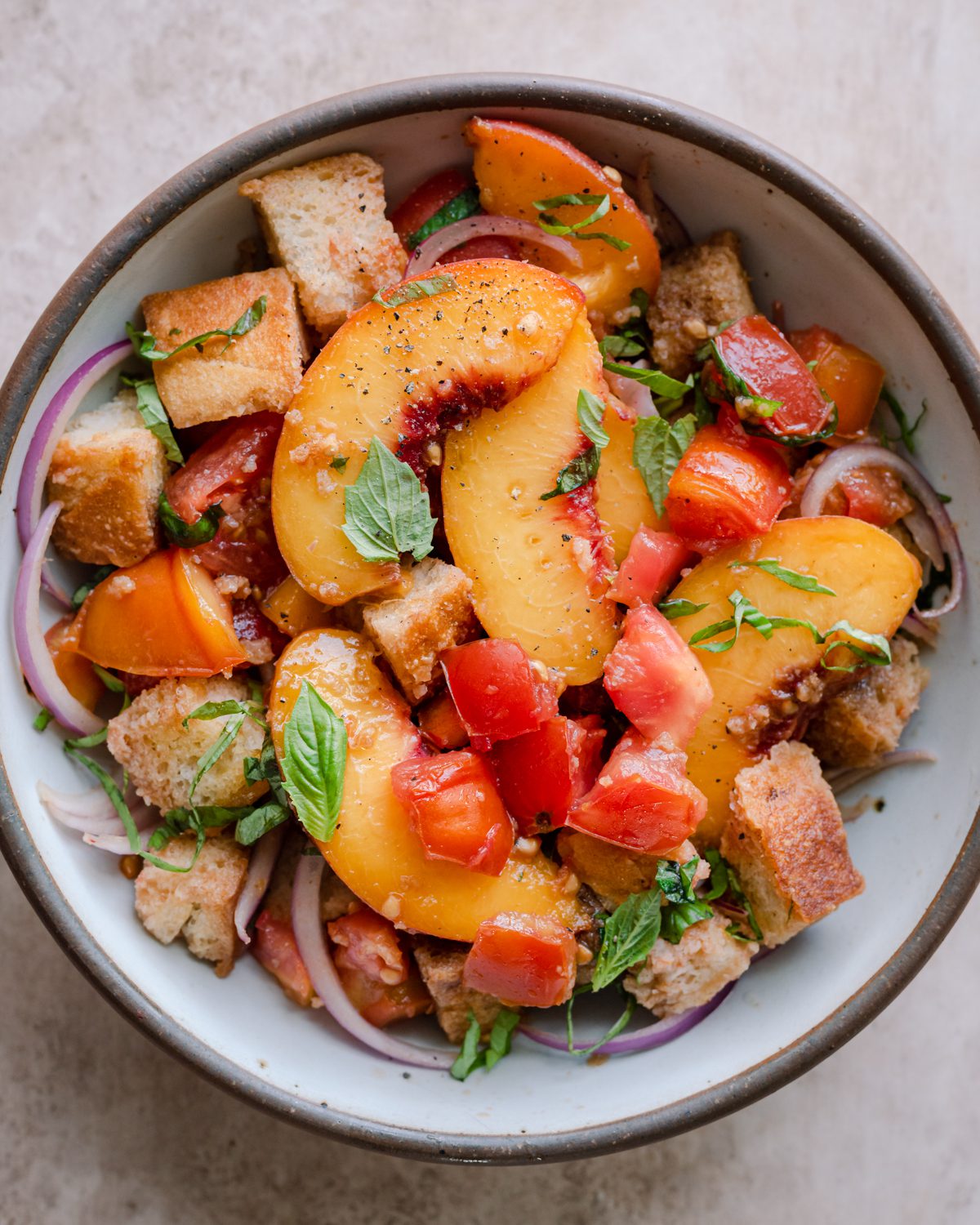 Peach panzanella salad in a bowl.