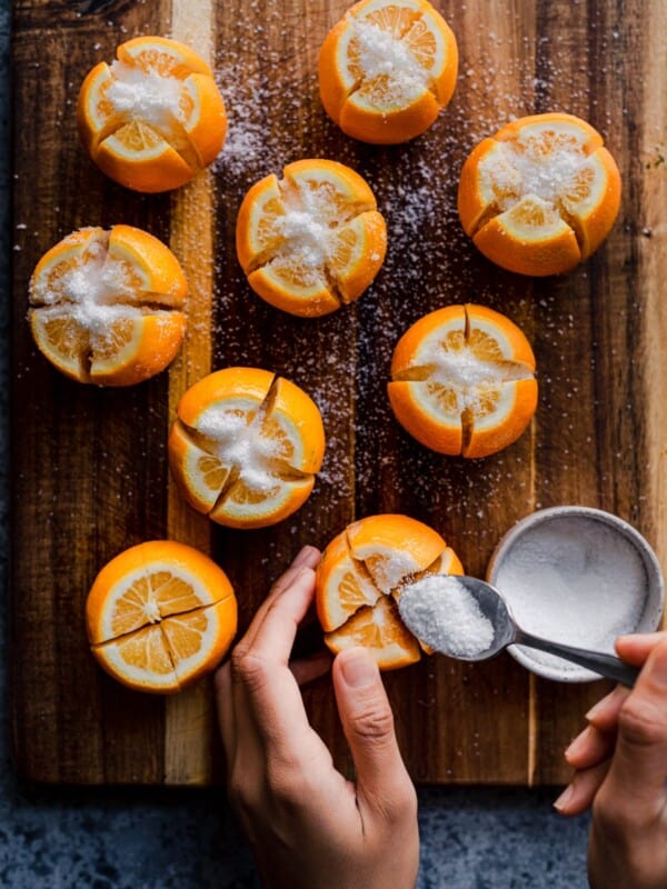 woman's hands spooning salt into sliced lemons for preserved lemons