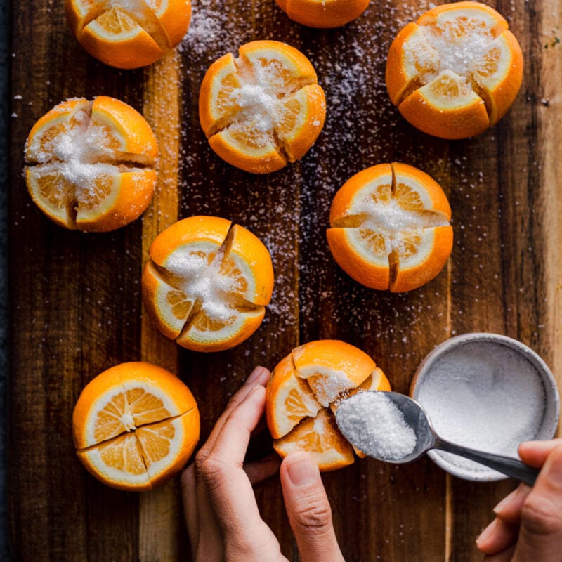 woman's hands spooning salt into sliced lemons for preserved lemons