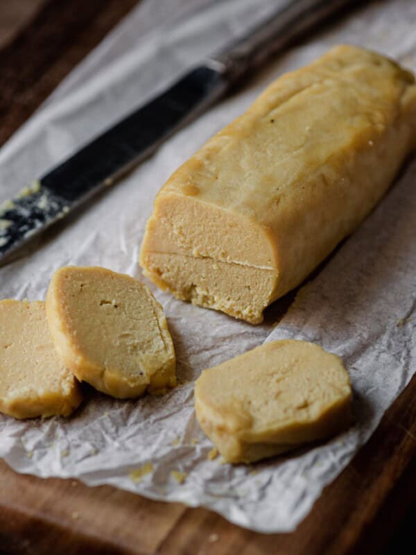 log of cashew cheese on parchment paper with knife.