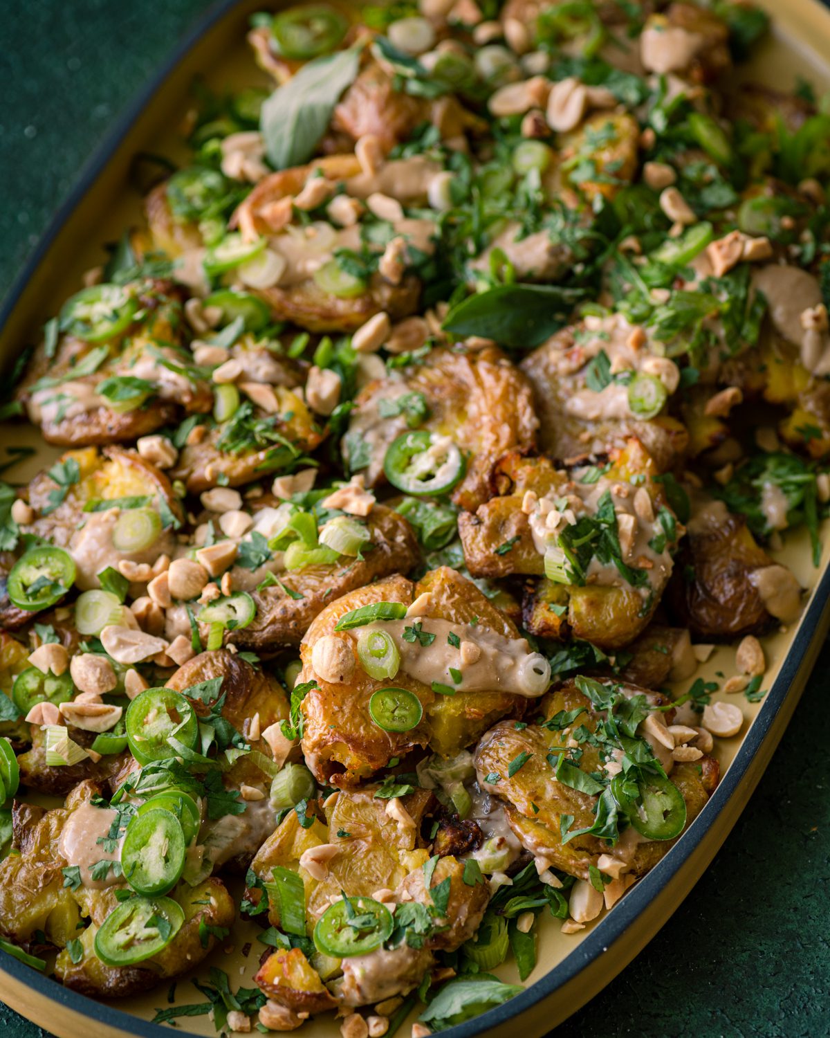 crispy smashed potatoes with ginger-tahini dressing, scallions, and fresh herbs.