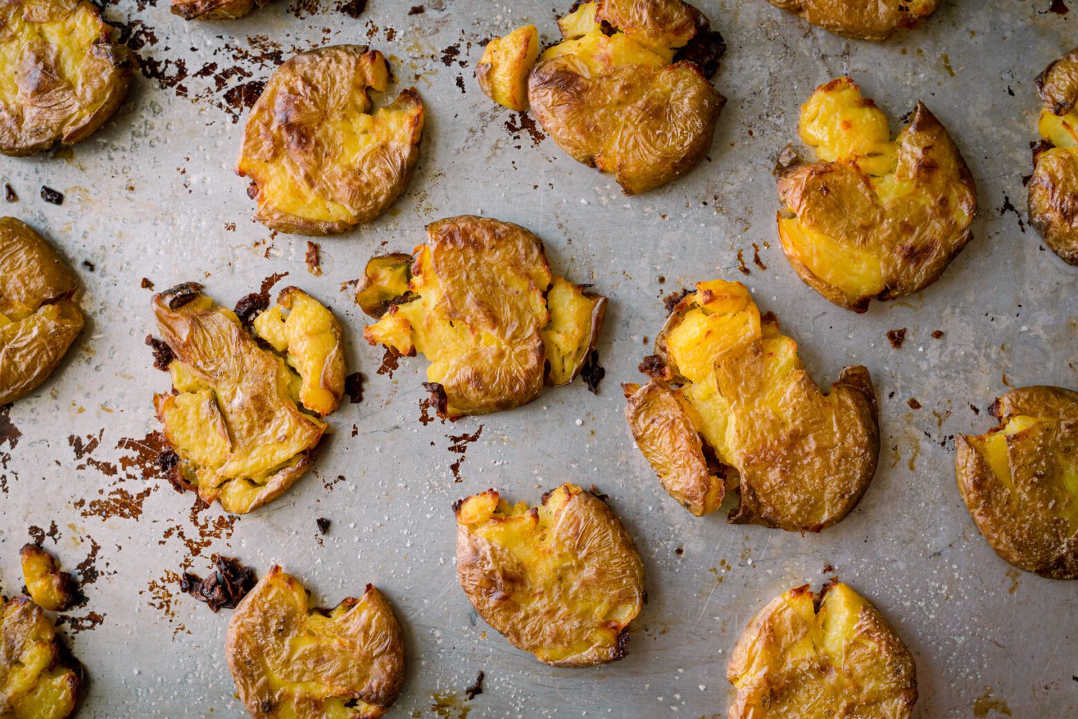 crispy smashed potatoes on a baking sheet with oil and salt 