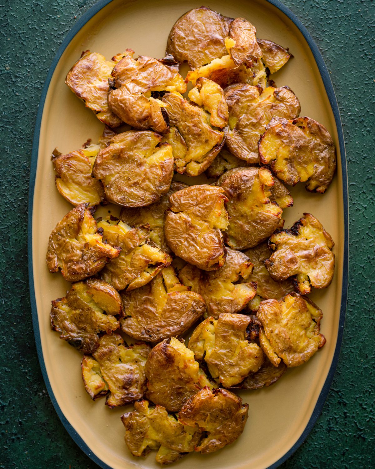 crispy smashed potatoes on yellow rimmed platter