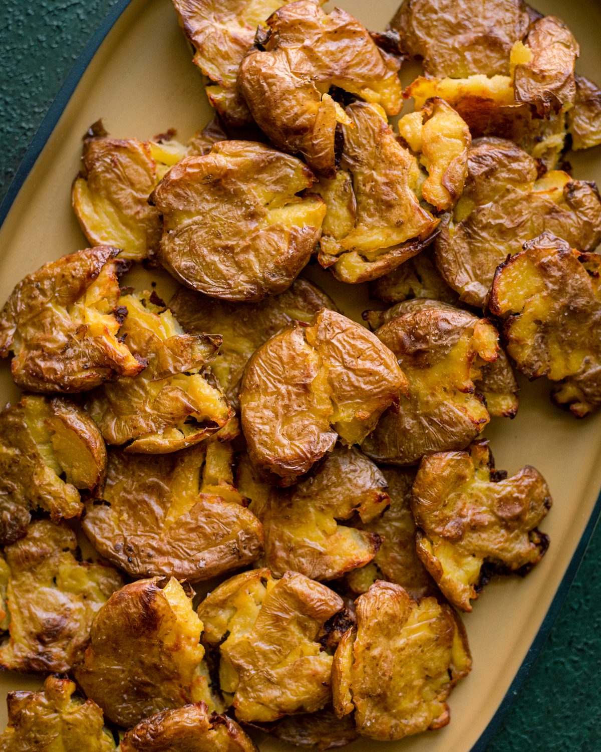 closeup of crispy smashed potatoes on a yellow platter