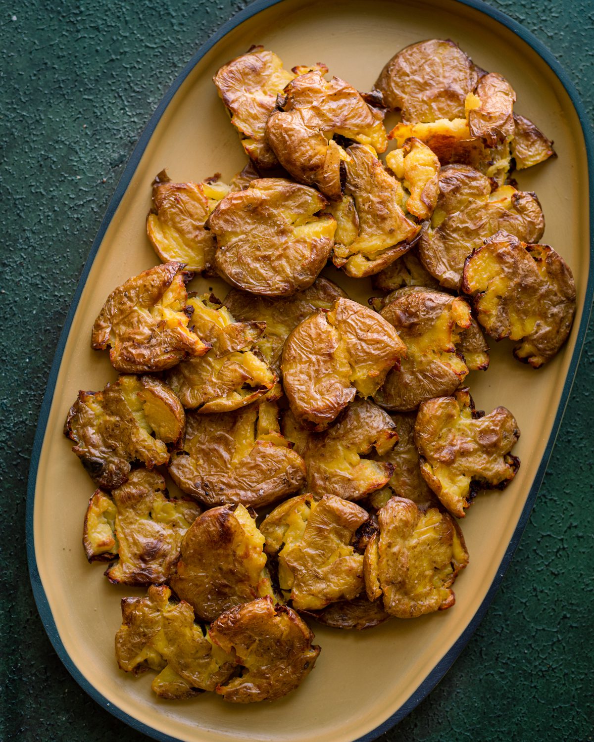 crispy smashed potatoes on a yellow serving platter