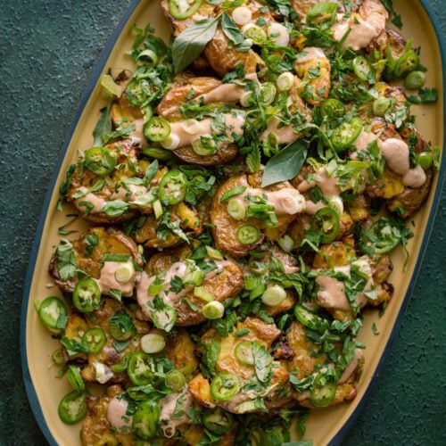 crispy smashed potatoes with ginger-tahini dressing and scallions and herbs.