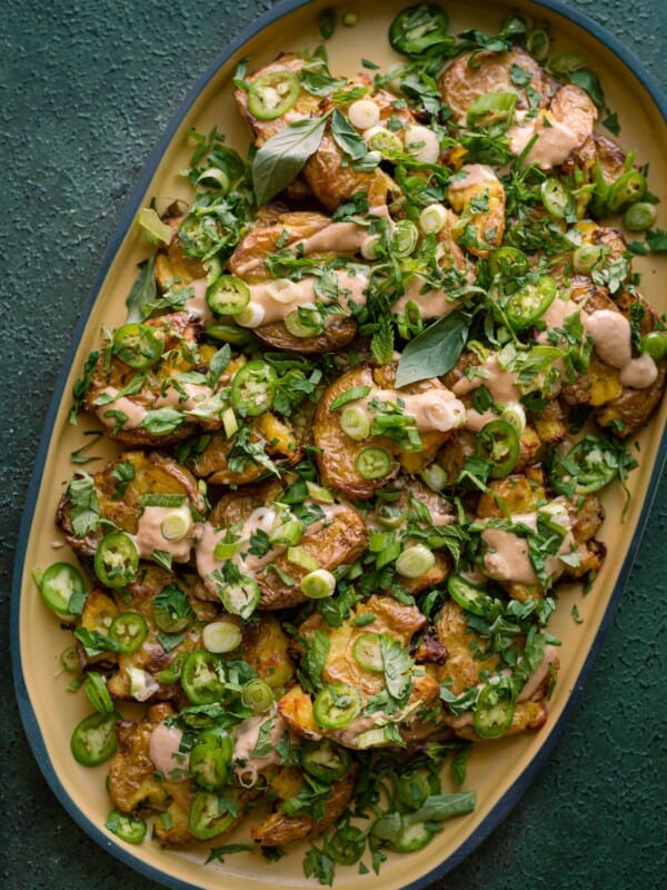 crispy smashed potatoes with ginger-tahini dressing and scallions and herbs.