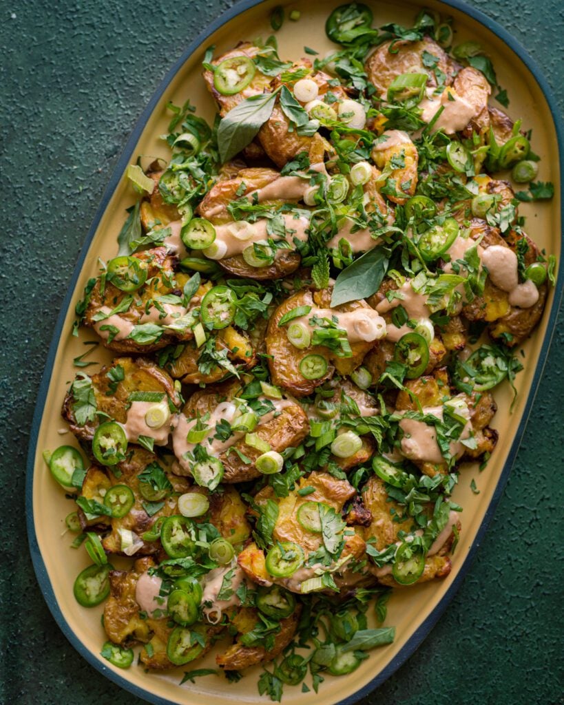 crispy smashed potatoes with ginger-tahini dressing and scallions and herbs
