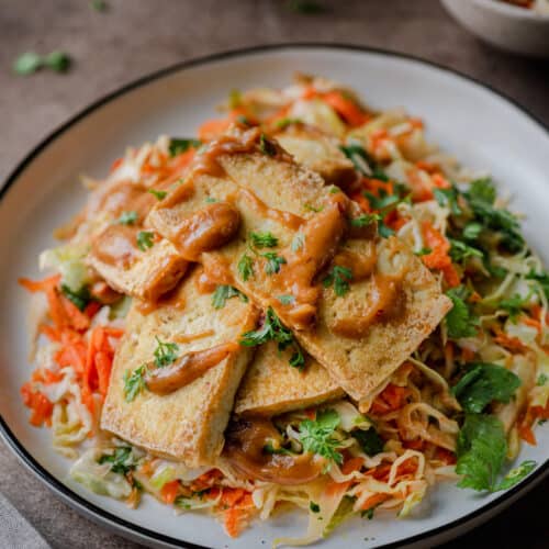 crispy tofu with peanut sauce over cabbage slaw